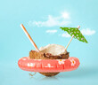 Half of a coconut with ring float, sun umbrella and cocktail straw on a blue background. Creative concept summer beach holiday
