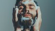 Young bearded man with eyes closed washes his face with foam. isolated on grey