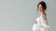 Caucasian pregnant woman with pregnancy belly, in soft white clothes