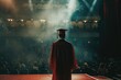 graduate standing alone on stage looking at the audience