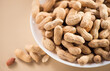 Peanuts. Unshelled nuts in a bowl close up. Roasted pile of peanuts in shell over beige background. Organic vegan, vegetarian food. Healthy nutrition concept. Top view