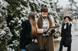 © qunica.com - A young man and woman browse a tablet in a wintry park, while a fashionable older woman looks on smiling, capturing togetherness and technology.