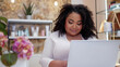 Closeup small business owner plus size African woman with dark skin and curly hair using laptop in her studio