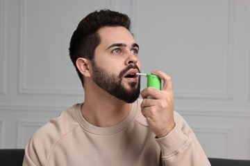 Sticker - Young man using throat spray at home