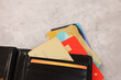 Many different credit cards and leather wallet on grey table, closeup