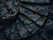 The Image Is Of A Rock With Deep Cracks And Holes, Giving It A Rough And Jagged Appearance. The Black Color Of The Rock Contrasts With The Orange And Yellow Hues Of The Cracks, Creating A Dramatic