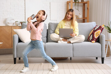 Canvas Print - Working young woman stressed of her noisy little daughter singing at home