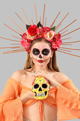 Poster - Young woman with painted skull on grey background. Celebration of Mexico's Day of the Dead (El Dia de Muertos)