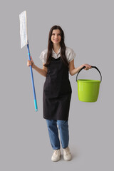 Wall Mural - Young woman with floor mop and bucket on grey background