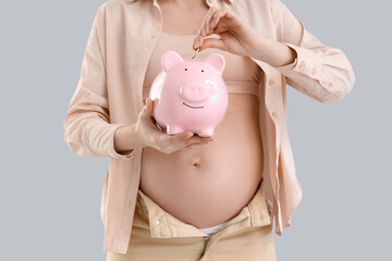 Canvas Print - Young pregnant woman putting coin into piggy bank on light background, closeup. Maternity Benefit concept