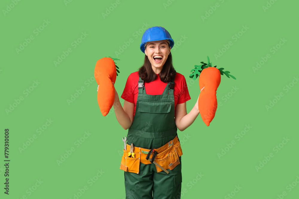 Happy female builder with toy carrots and tools on green background. Easter celebration