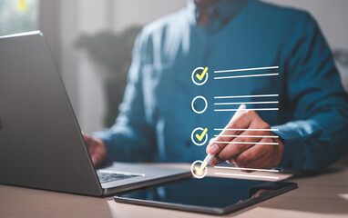 checklist, list, compliance, intelligence, management, marketing, strategy, working, information, office. A man is using a laptop and tablet to check off items on a list. Concept of productivity.