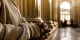 Fototapeta  - Praying hands clasped together in a church aisle, invoking a sense of peace and piety in a serene, light-filled religious sanctuary.