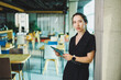 © DSMT - A cute woman in a black suit with a tablet in her hands is standing in a modern office.