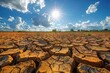 Cracked soil under a bright sun conveys the stark reality of drought in a cloud-strewn sky.