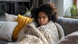 © pkproject - Young African Woman Sitting Alone Thoughtfully on Cozy Living Room Sofa