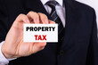 © PRO Balance - Businessman shows a sign with the text PROPERTY TAX. Business concept