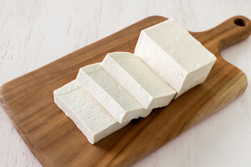 Sliced raw tofu on a brown cutting board