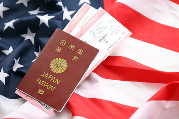 Wall Mural - Japan passport with airline tickets on American US flag close up. Tourism and travel concept