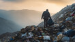 Man carrying a bag of trash in a vast landfill, copy space