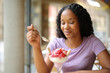 Black woman eating strawberry in a terrace