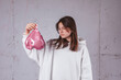 © Westend61 - Girl holding deflated heart shaped pink balloon in front of cement background