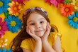 Smiling girl in on yellow background. Cheerful happy child in front of flowers
