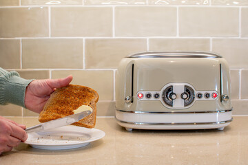 A piece of toast with butter on a knife about to be spread. Breakfast food image with a green kitchen theme. 