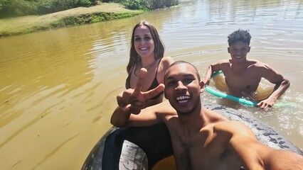 Poster - Selfie, swimming and friends in river in nature on holiday, summer vacation and weekend. Live streaming, camp and portrait of people on fun adventure for content creation, vlog and travel influencer