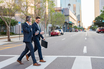 Wall Mural - Businessmen talking on city street. Two colleagues business men walking outdoors on the street. Cheerful business conversation. Two businessmen walking outside business center, having conversation.