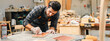 © chokniti - Diligently skilled man work with wood in carpenter's shop, using tools and equipment to transform timber planks into bespoke wooden pieces, craftsmen workshop with natural material, furniture industry