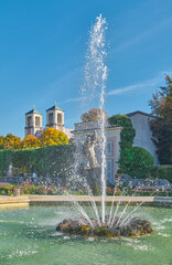 Poster - Salzburg, Austria -  October 6, 2022: The  fountain and garden of the Mirabell palac with the St Andrew bell tower in the background