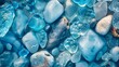 Top view close-up of vibrant blue sea glass and polished stones on the shore, illuminated by gentle summer light
