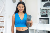 Fototapeta  - Beautiful latin american woman with yoga mat ready for class at gym
