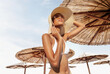 Fashion woman wear sun straw hat under beach umbrella of straw concept of summer beach holiday, vacation travel or sun skin care protection, banner with copy space for text or logos on sky background