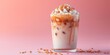 Iced caramel latte, macchiato, coffee with whipped cream and caramel syrup in glass with ice cubes on pastel pink background, copy space