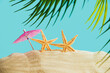 Starfish with a sun umbrella and a palm tree on a sandy beach.