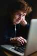 An old woman sits with her laptop.