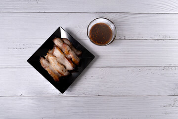 Juicy grilled pork neck and spicy Thai style sauce on white wood background. Thai food