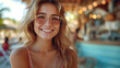 Joyful young woman with pink sunglasses smiling at the camera. Beach bar and leisure concept with a focus on happiness and summer vibes