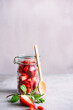 Frische Erdbeeren in einem Einmachglas mit einem Holz Löffel auf einem grauen Kachel Tisch. 