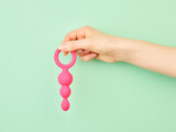Fototapeta Storczyk - Woman's hand holding adult sex toy over mint background