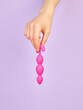 Woman's hand holding adult sex toy over violet background