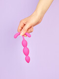 Fototapeta Łazienka - Woman's hand holding adult sex toy over violet background