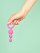 Woman's hand holding adult sex toy over mint background