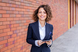 Fototapeta Desenie - Portrait of a successful business woman in front of modern business building.
Young manager poses outside. Female business leader.
