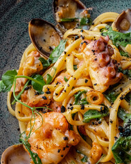 Pasta with various seafood in a gray plate close-up.