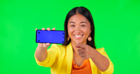 Sticker - Woman face, green screen and hand pointing to phone mockup with tracking markers on studio background. Portrait, space and asian lady person showing product placement for news or how to steps for app