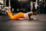 Fototapeta Kwiaty - A muscular black sportswoman in shape practicing pushups at gym.