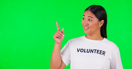 Canvas Print - Volunteer, green screen and a woman pointing at space for advertising, charity or information. Face of happy asian person with a hand and tshirt for nonprofit project, NGO help or donation in studio